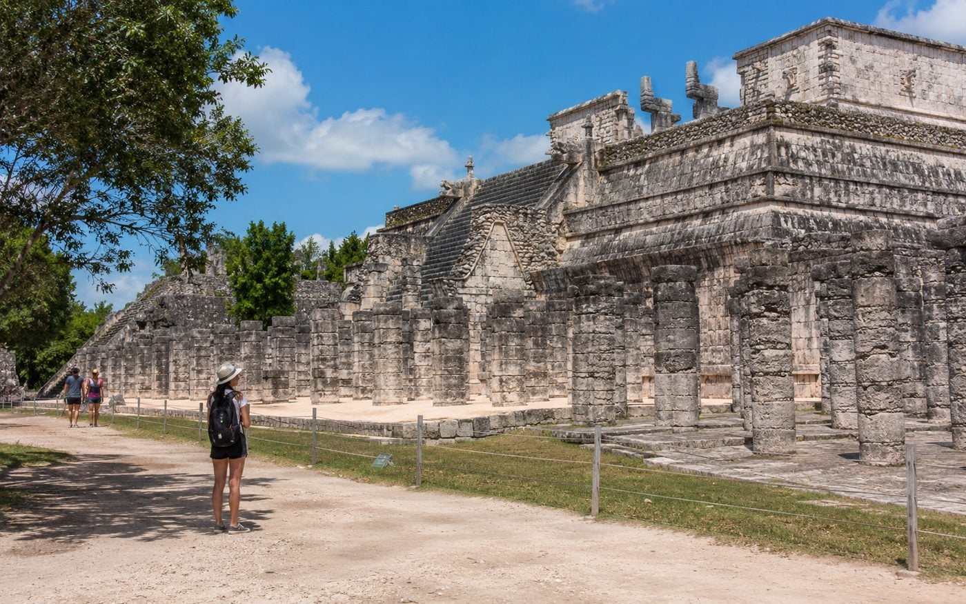 Temple of the Warriors and rows of stone columns at Chichén Itzá under a clear sky.