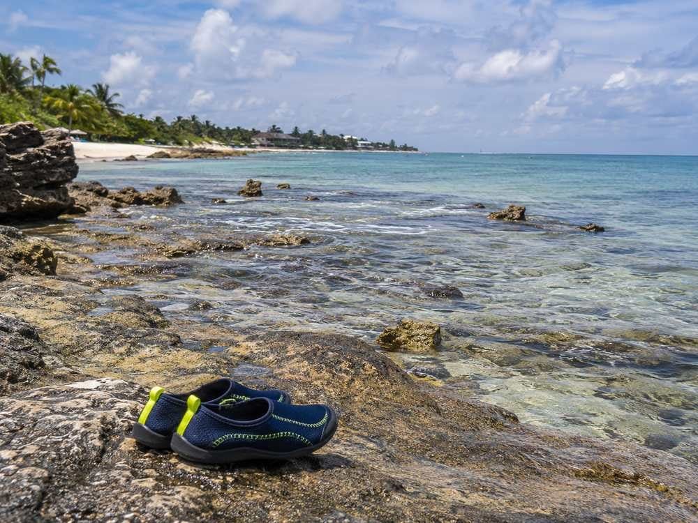 Rockier shoreline of Half Moon Bay with water shoes placed near the edge.