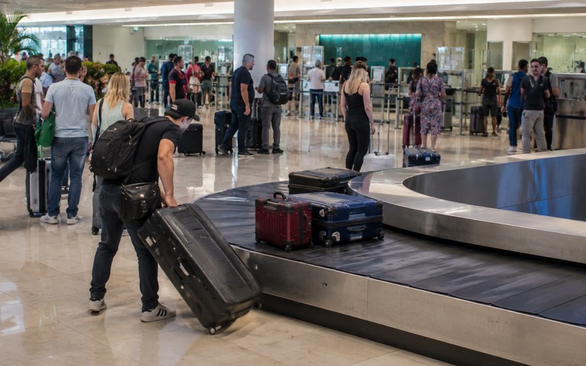 Travelers collecting luggage at a busy airport baggage claim area.