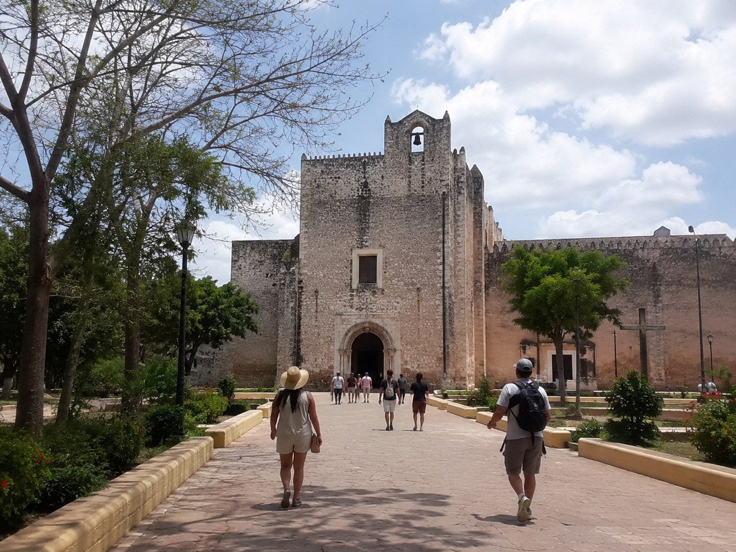 Pedestrians walking respectfully along Calzada de los Frailes toward Barrio de Sisal.
