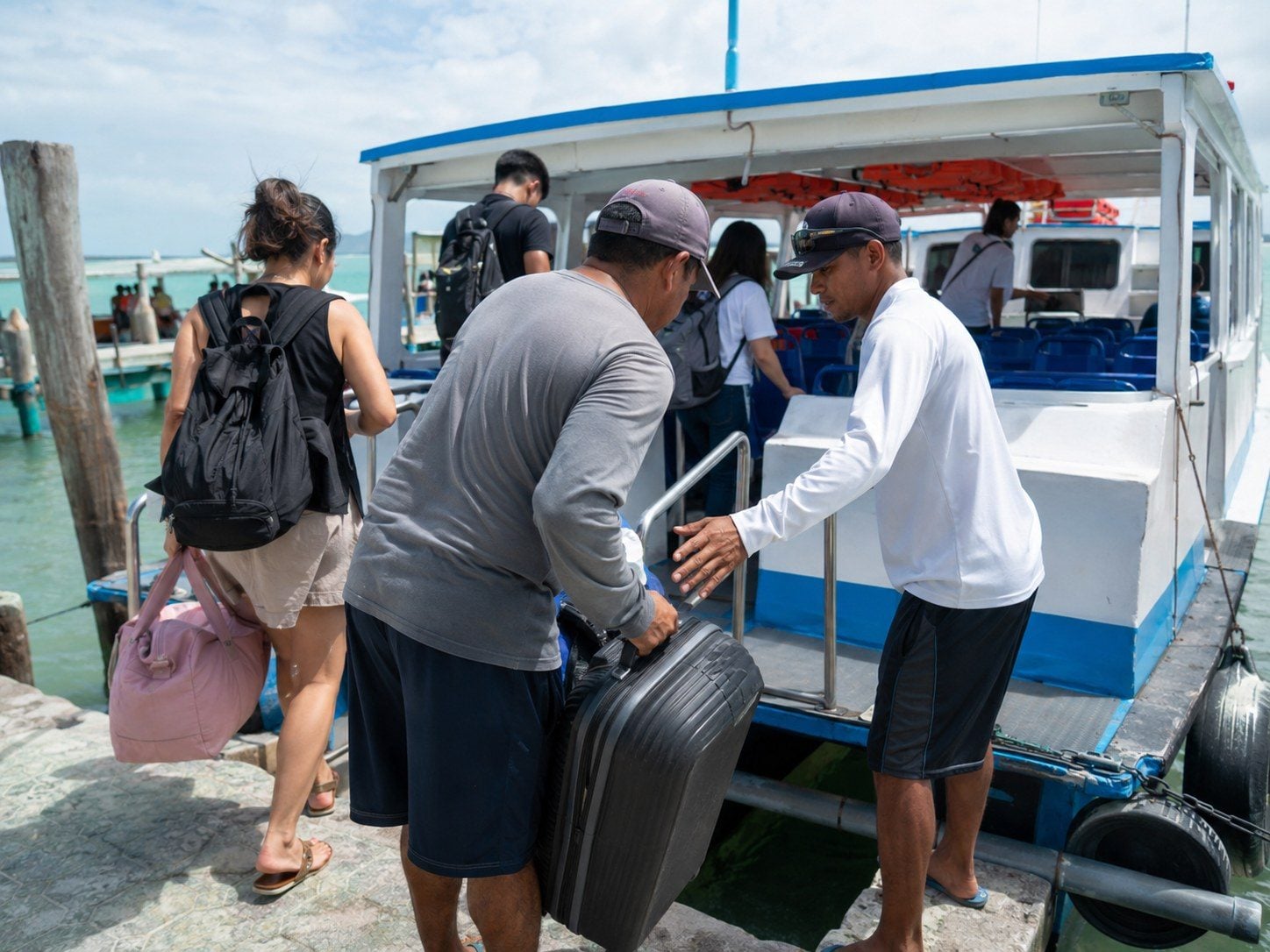 Ferry crew and passengers managing luggage during boarding for Holbox.