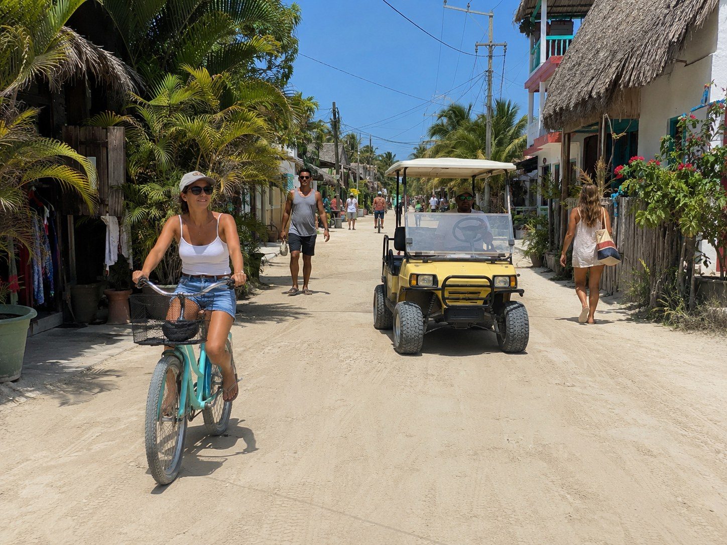 Bicycles and cart-style taxis moving through a sandy street in central Holbox.