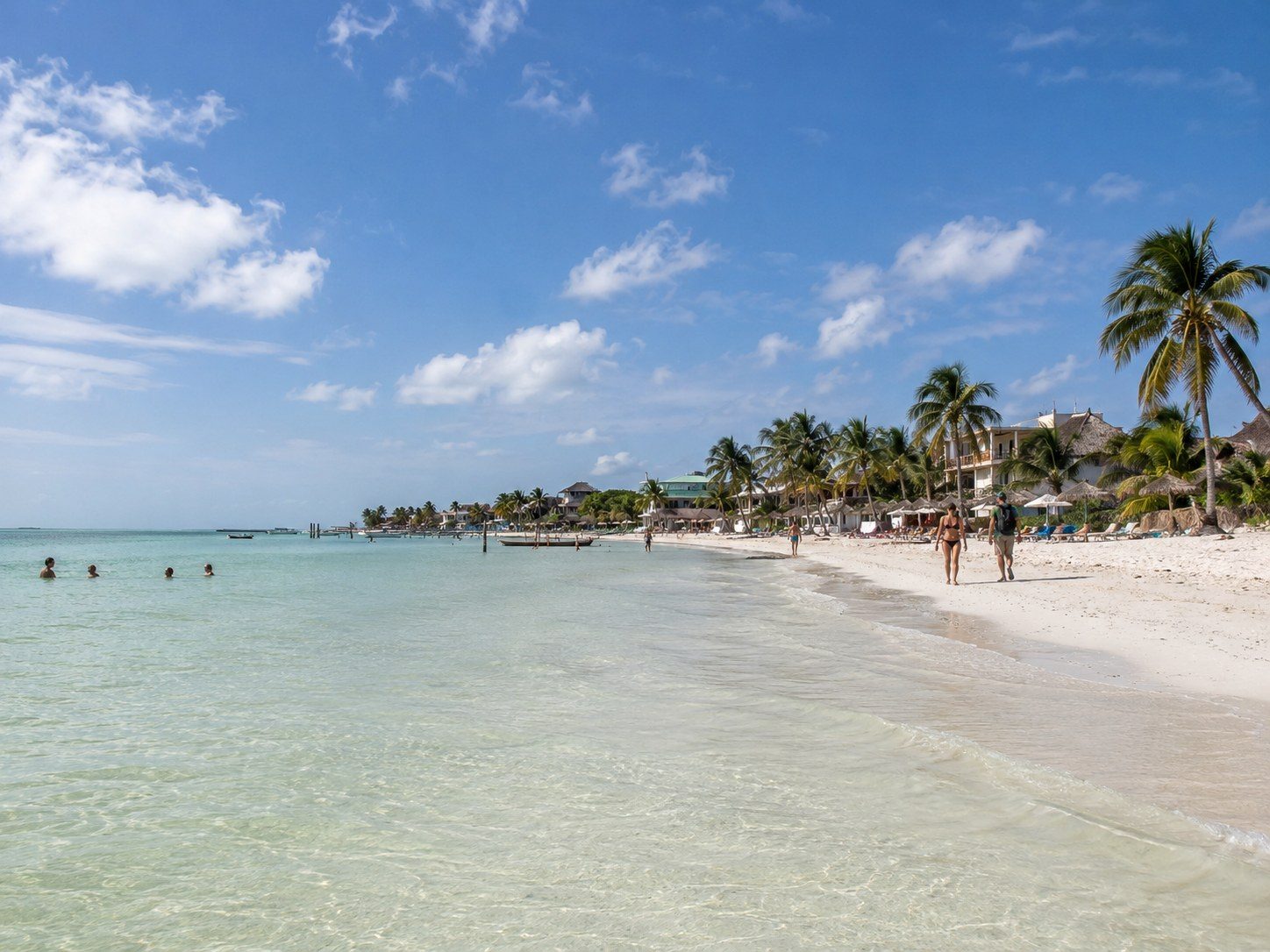 Wide view of the main Holbox beach near town with shallow water and public shoreline.