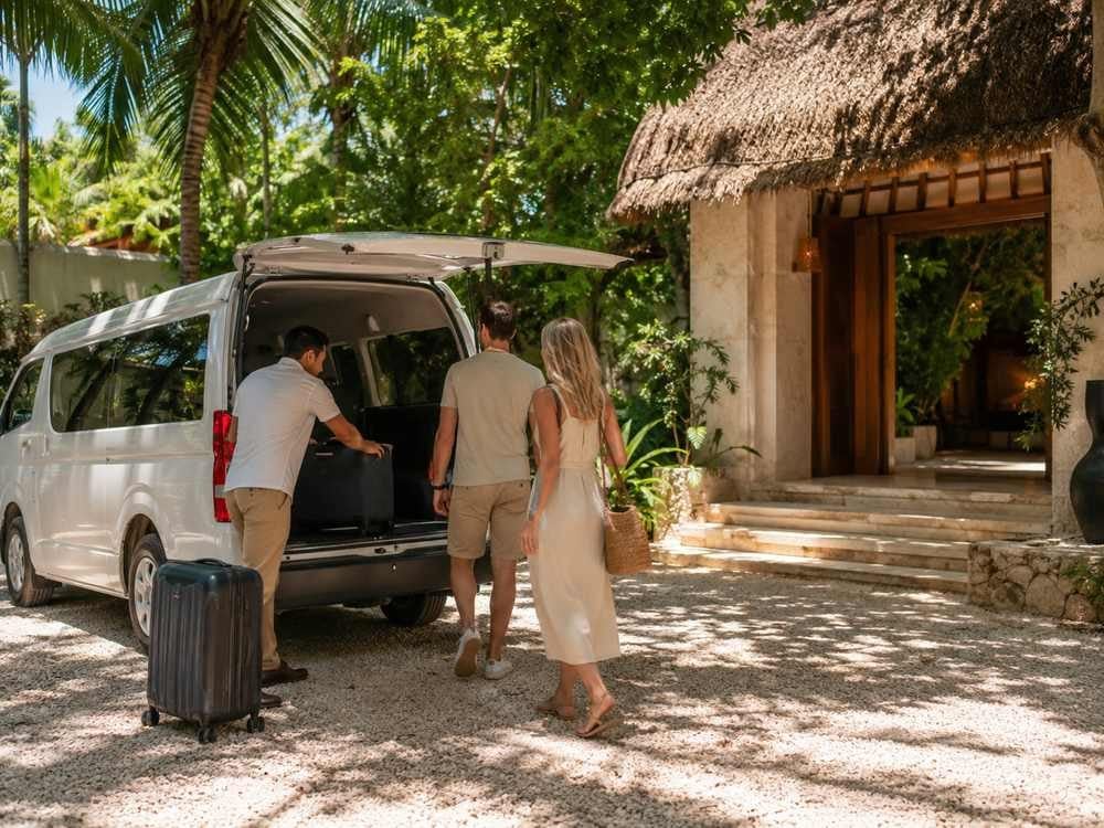 Private transfer van arriving at a tropical lodging entrance with luggage.