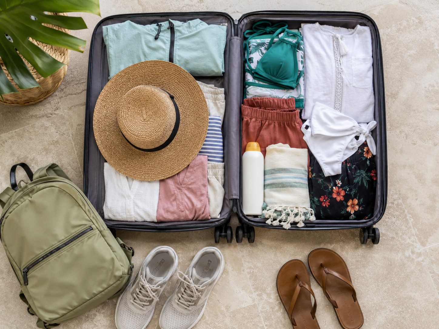 Open suitcase packed with lightweight clothing, swimwear, hat, walking shoes and sandals for Cancún.