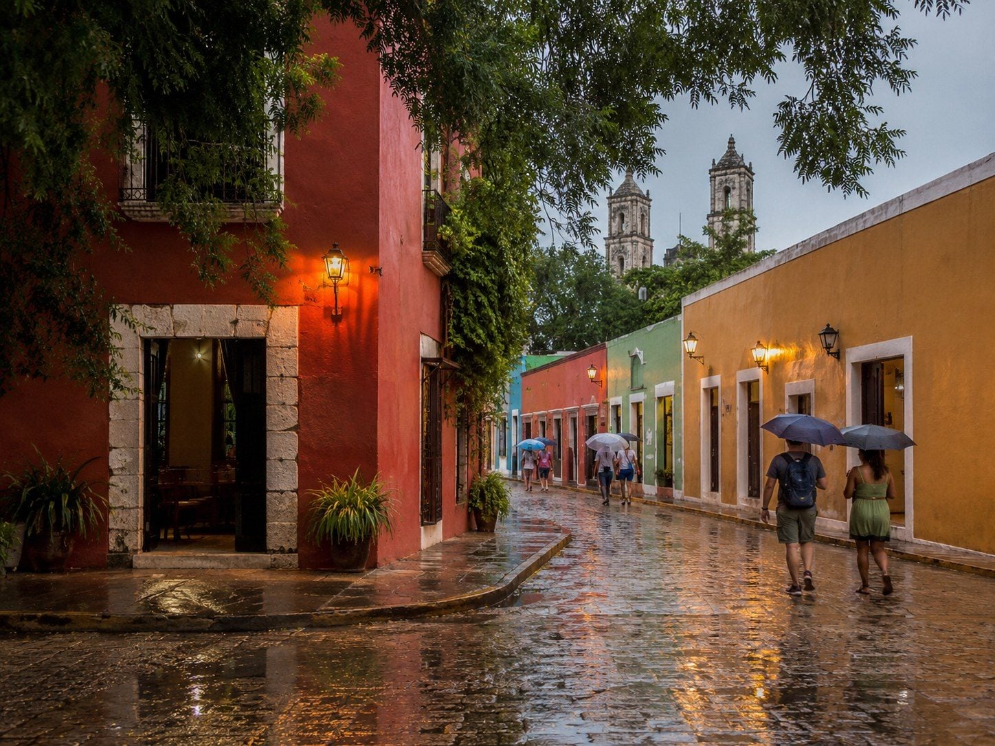 A brief tropical shower over Valladolid with pedestrians using safe rain protection.