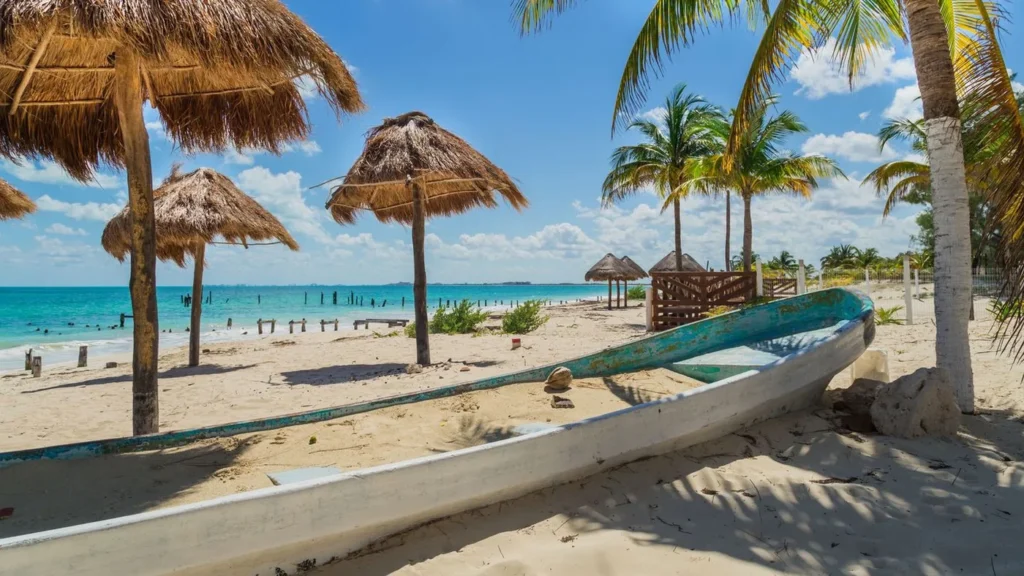 Quiet beach on Isla Mujeres with a traditional boat, palms and turquoise water