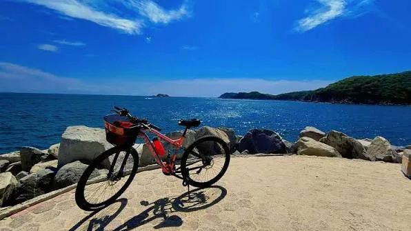 A bicycle resting on a rocky Caribbean coastline