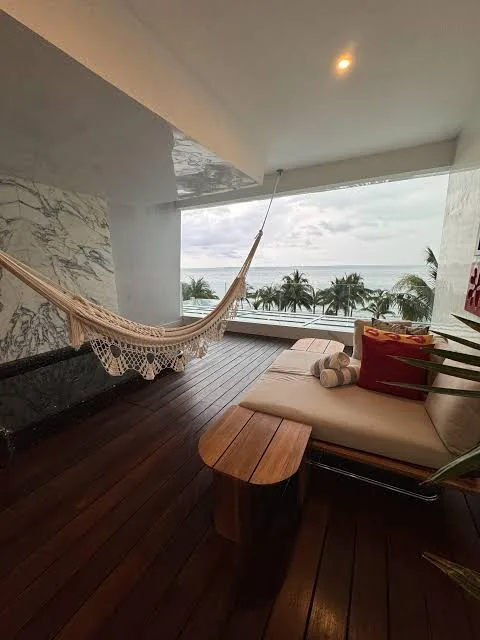 A hammock on a quiet balcony overlooking palms and the sea