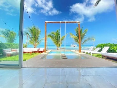 A bright pool terrace with wooden swings and the sea beyond