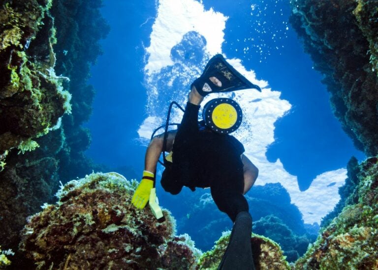 Scuba diver ascending through coral formations at Palancar Reef in Cozumel.