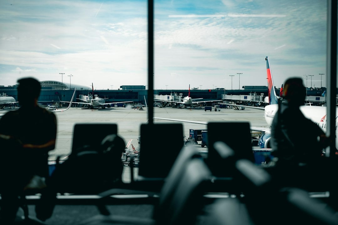 Travelers waiting at an airport departure gate with aircraft visible outside
